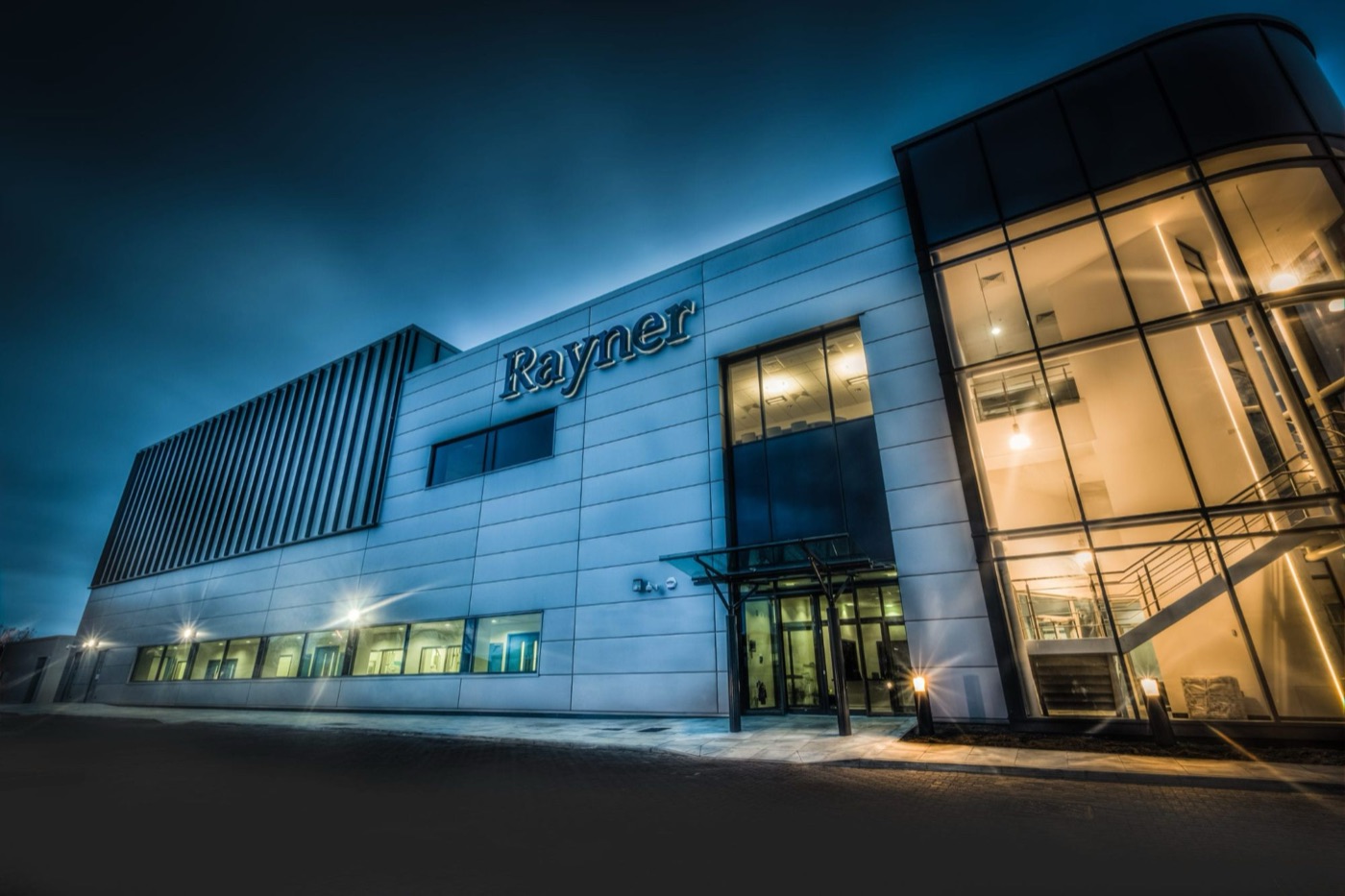 Sede da Rayner no Reino Unido ao anoitecer, fachada iluminada
